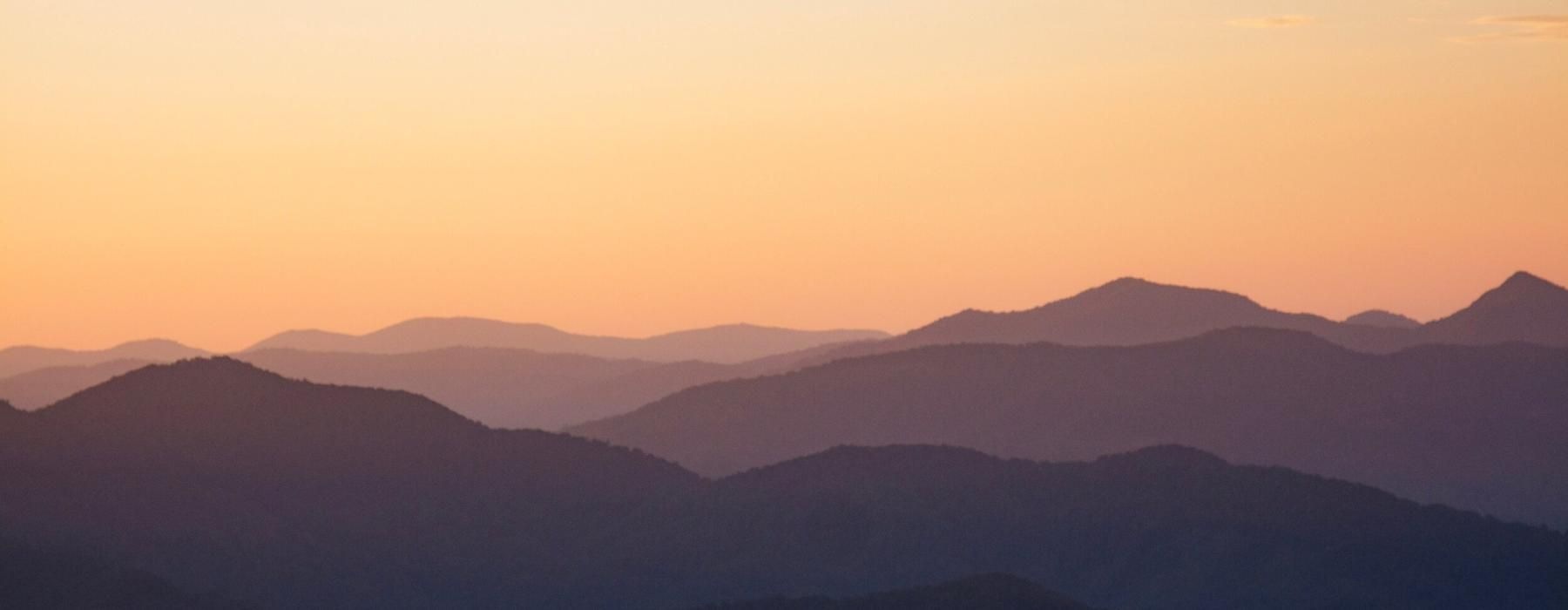 a landscape with hills and a sunset