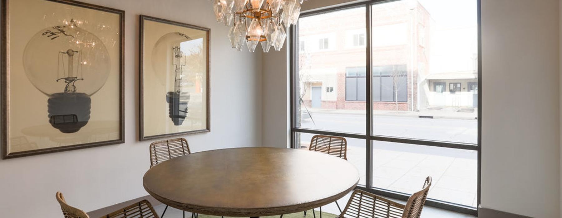 a clubhouse room with a table, chairs and a chandelier above it
